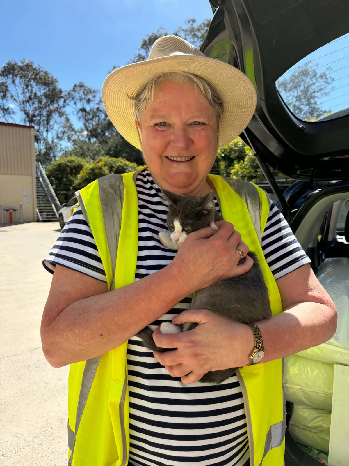 A volunteer holding a small animal beside a vehicle