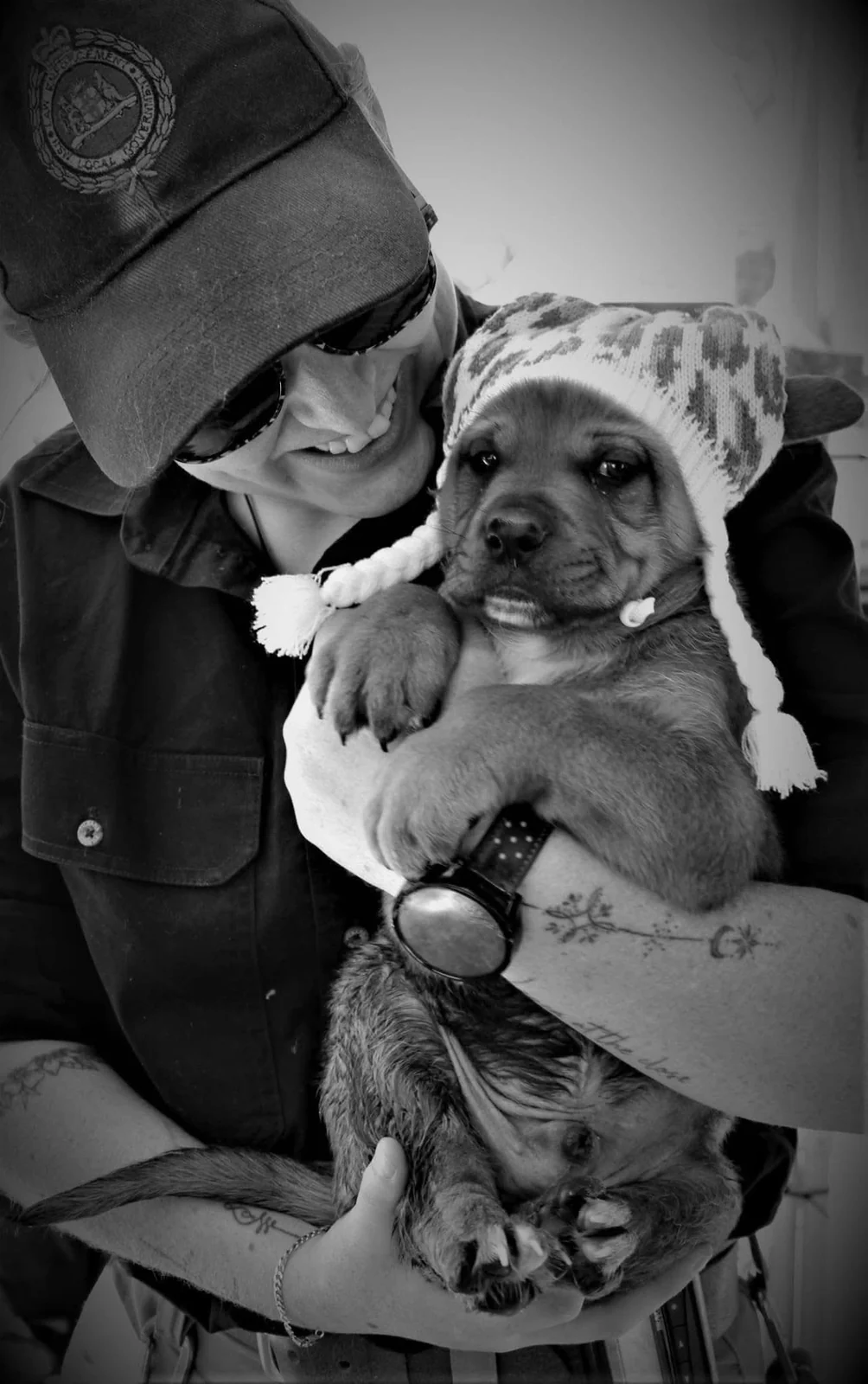 A volunteer holding a puppy wearing a knitted hat