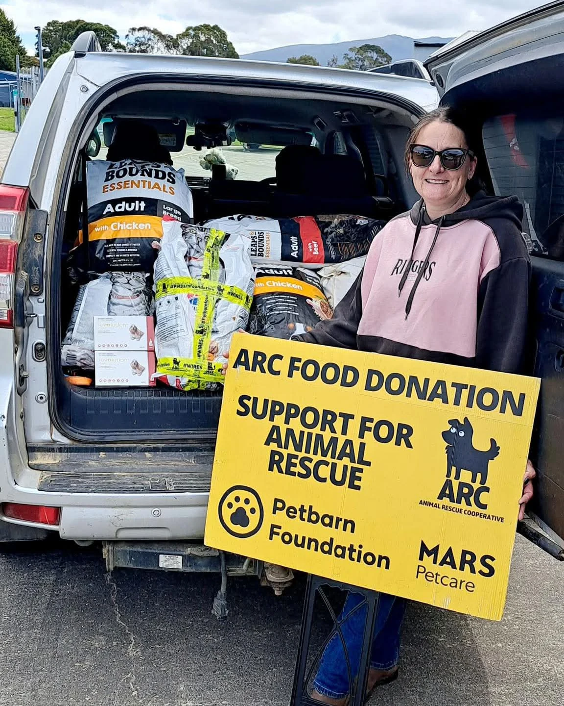 A volunteer beside a van loaded with donated supplies