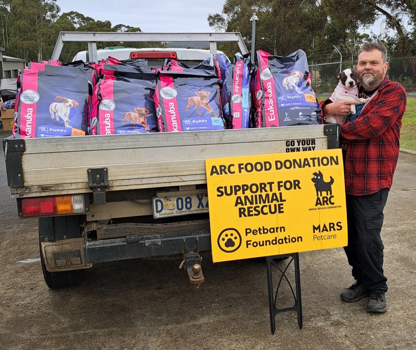 A volunteer and dog beside donated pet food